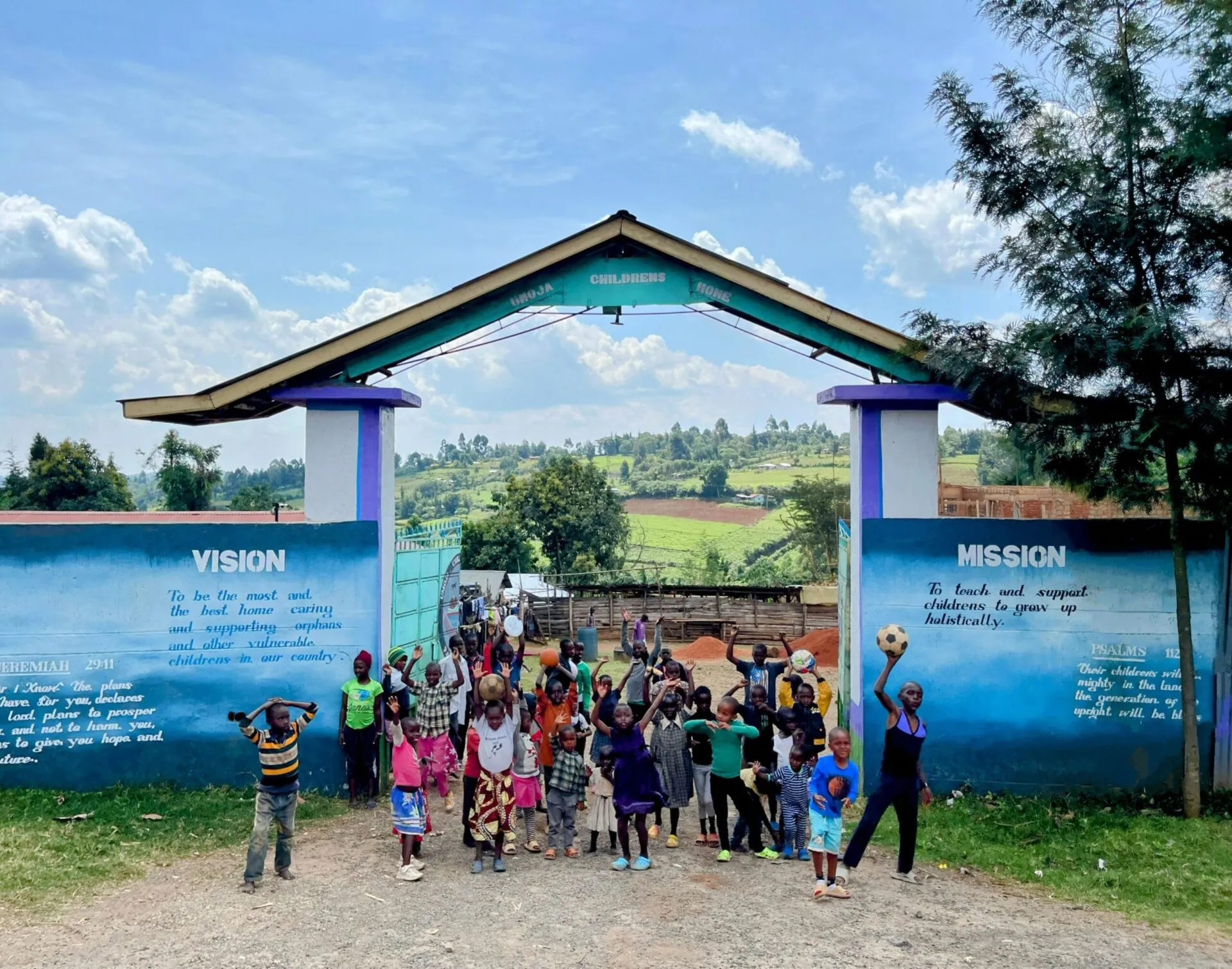 The painted entrance gate of Umoja Children's Home with children playing in front